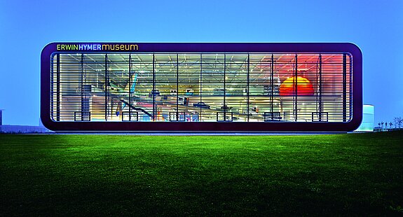 ehm_gebäude_bei_nacht odernes, leuchtendes Gebäude des Erwin Hymer Museums bei Nachtaufnahme.