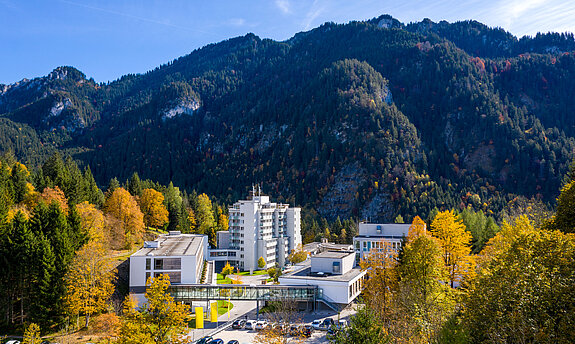 Klinik Oberammergau (Außenaufnahme) mitten im Herbstwald, im Hintergrund ist der Berg Laber zu sehen