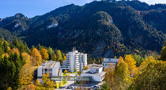 Klinik Oberammergau (Außenaufnahme) mitten im Herbstwald, im Hintergrund ist der Berg Laber zu sehen