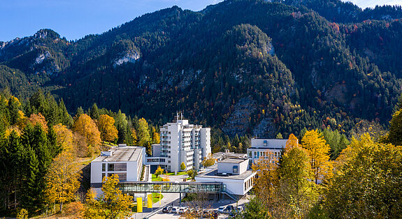 Klinik Oberammergau (Außenaufnahme) mitten im Herbstwald, im Hintergrund ist der Berg Laber zu sehen