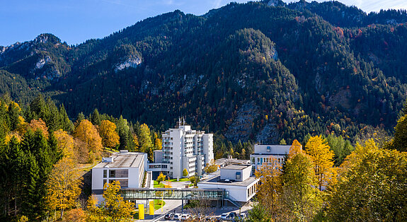 Klinik Oberammergau (Außenaufnahme) mitten im Herbstwald, im Hintergrund ist der Berg Laber zu sehen