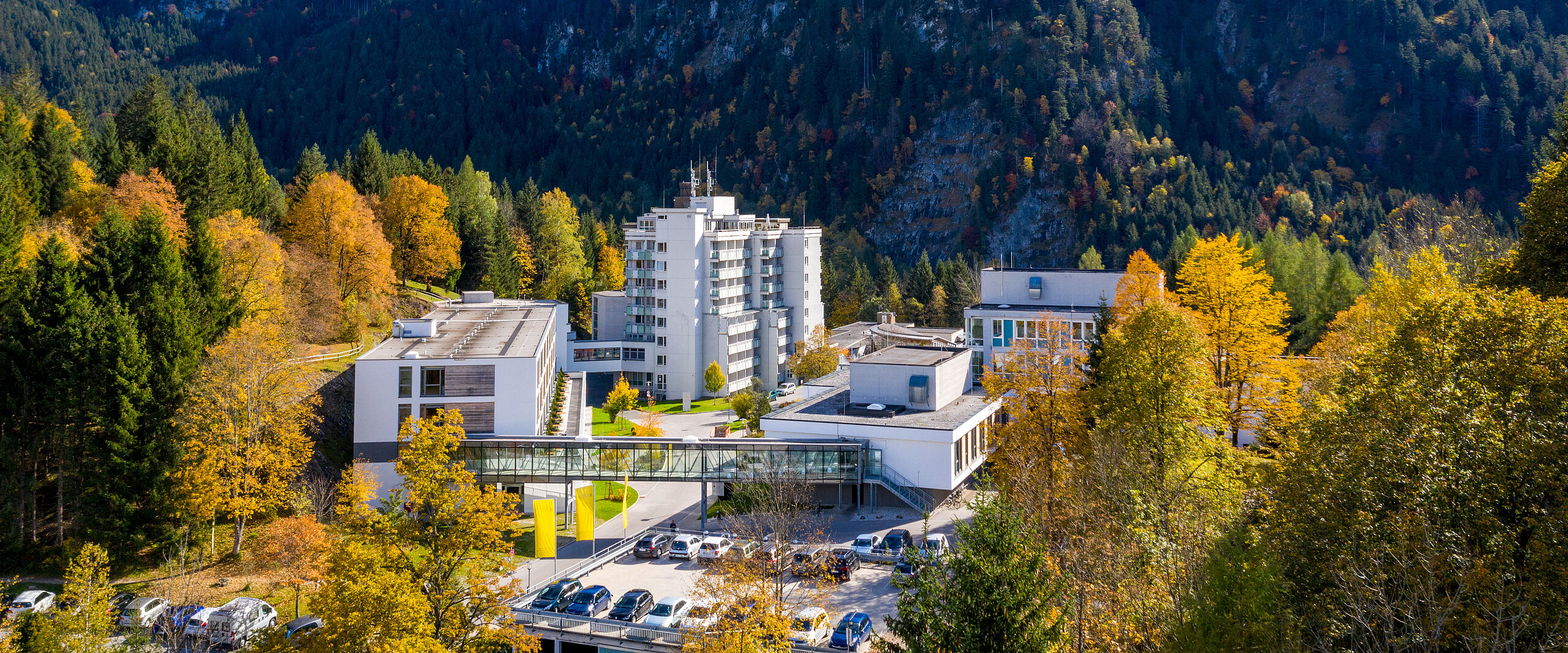 Klinik Oberammergau (Außenaufnahme) mitten im Herbstwald, im Hintergrund ist der Berg Laber zu sehen