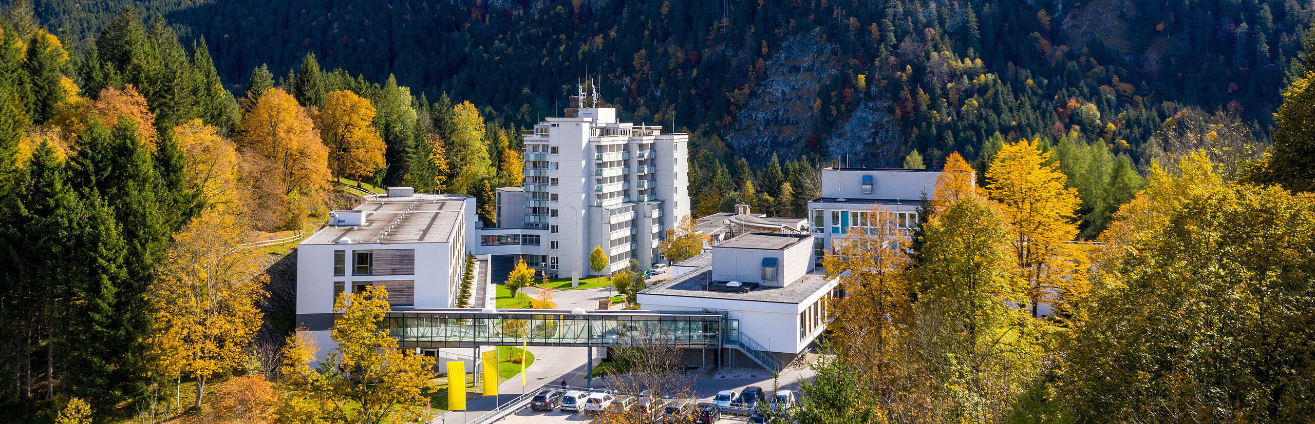 Klinik Oberammergau (Außenaufnahme) mitten im Herbstwald, im Hintergrund ist der Berg Laber zu sehen