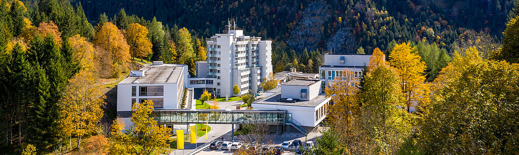Klinik Oberammergau (Außenaufnahme) mitten im Herbstwald, im Hintergrund ist der Berg Laber zu sehen