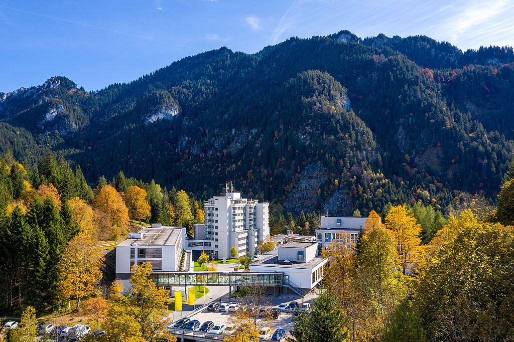 Klinik Oberammergau (Außenaufnahme) mitten im Herbstwald, im Hintergrund ist der Berg Laber zu sehen