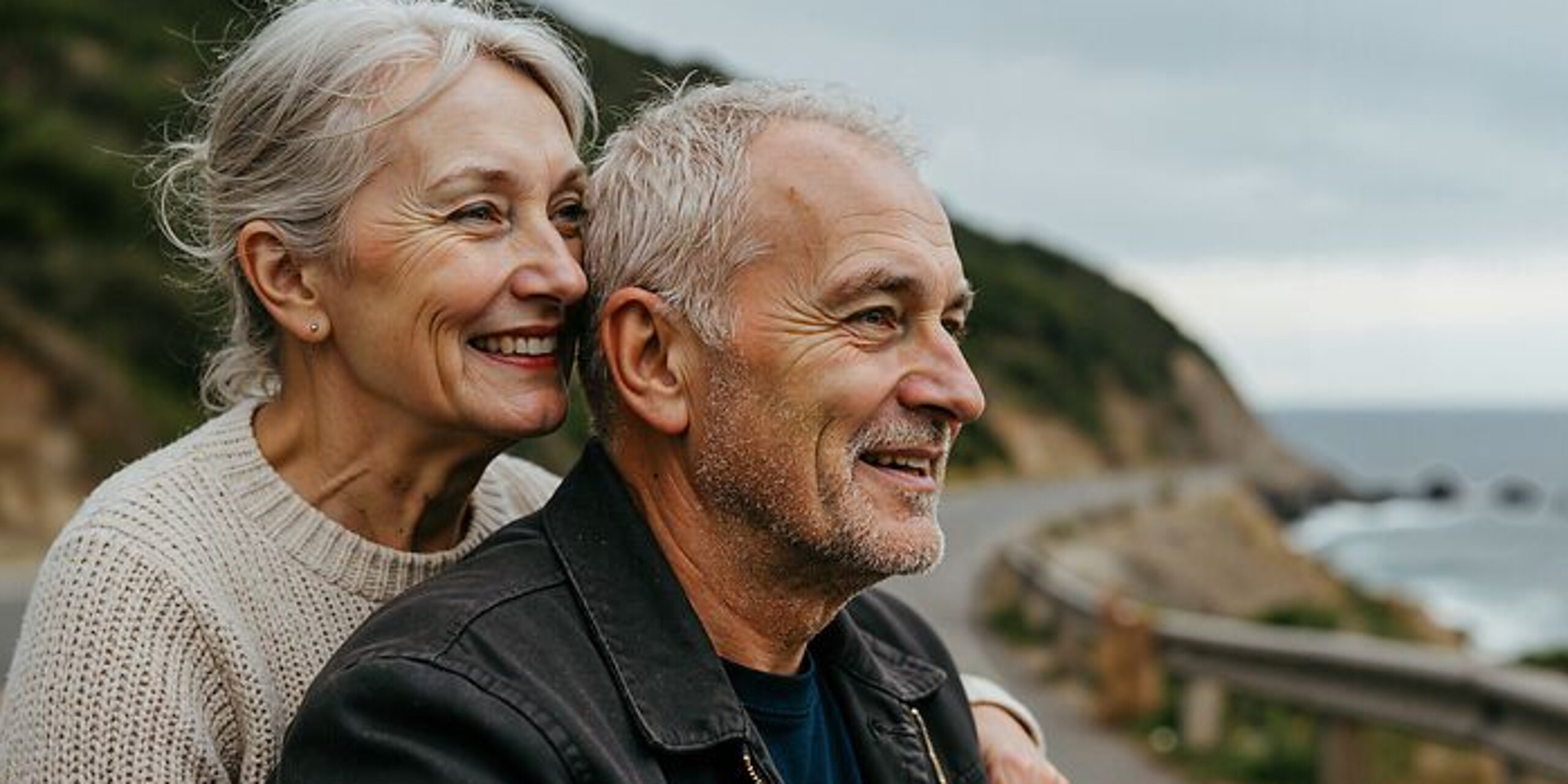 Ein Ehepaar im Rentenalter schaut gemeinsam auf das Meer hinaus.
