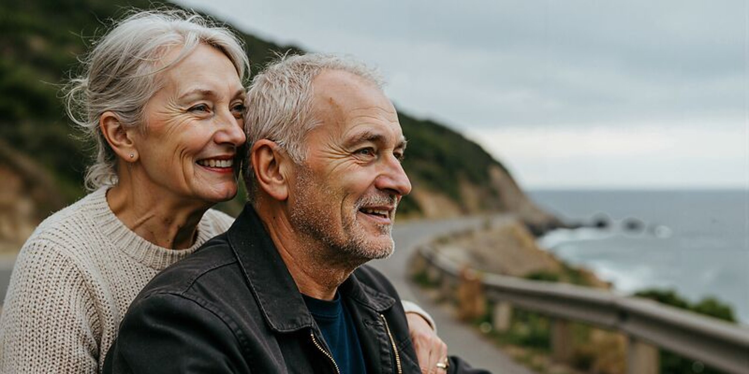 Ein Ehepaar im Rentenalter schaut gemeinsam auf das Meer hinaus.