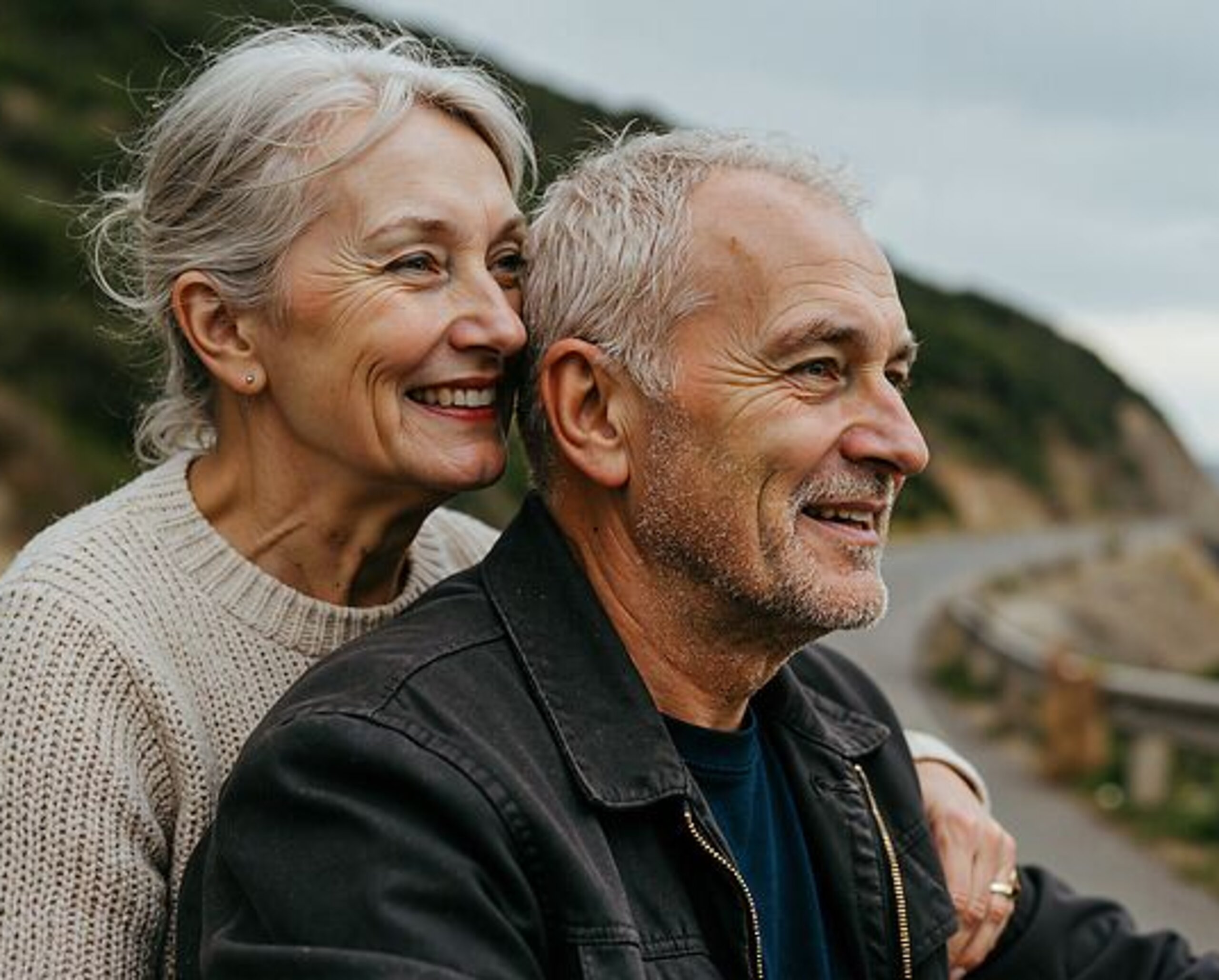 Ein Ehepaar im Rentenalter schaut gemeinsam auf das Meer hinaus.