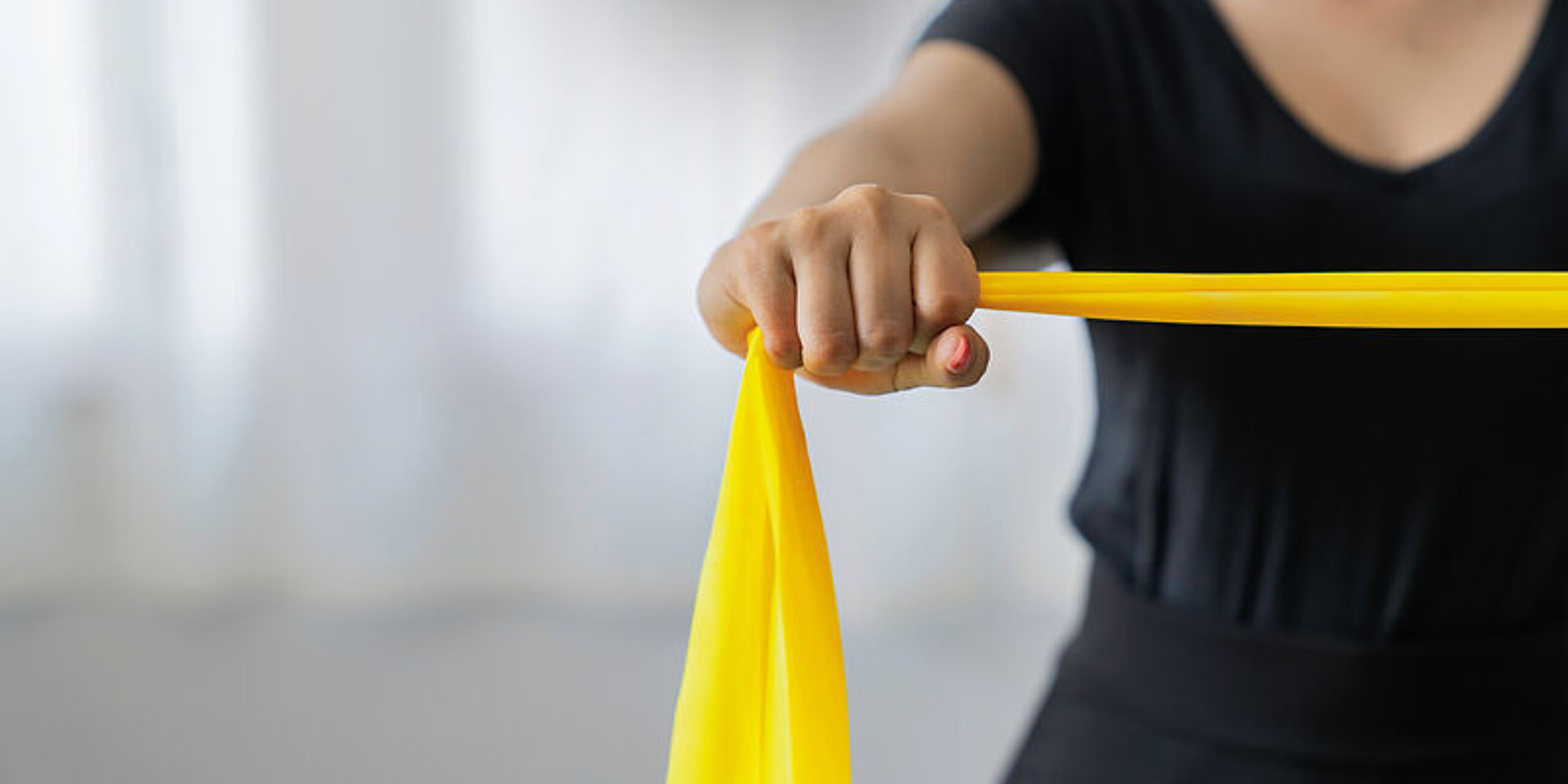 Eine Patientin macht Übungen mit einem gelben Therraband.