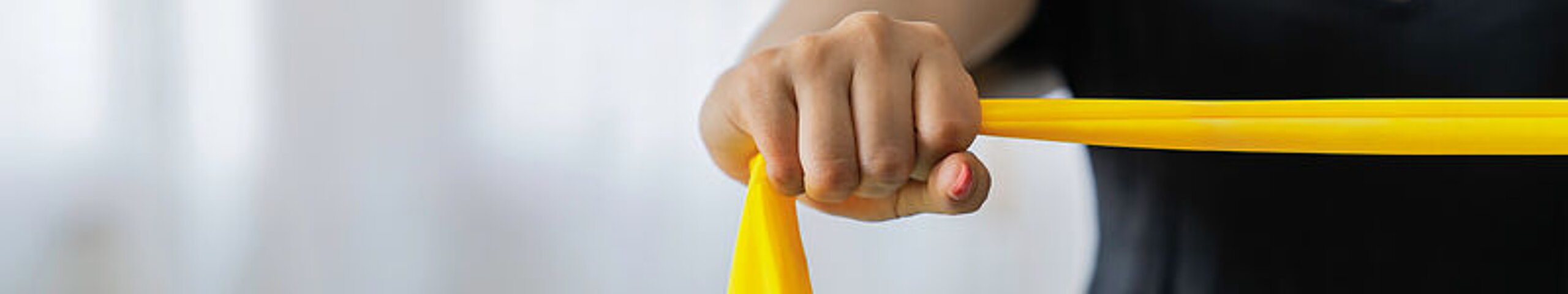 Eine Patientin macht Übungen mit einem gelben Therraband.