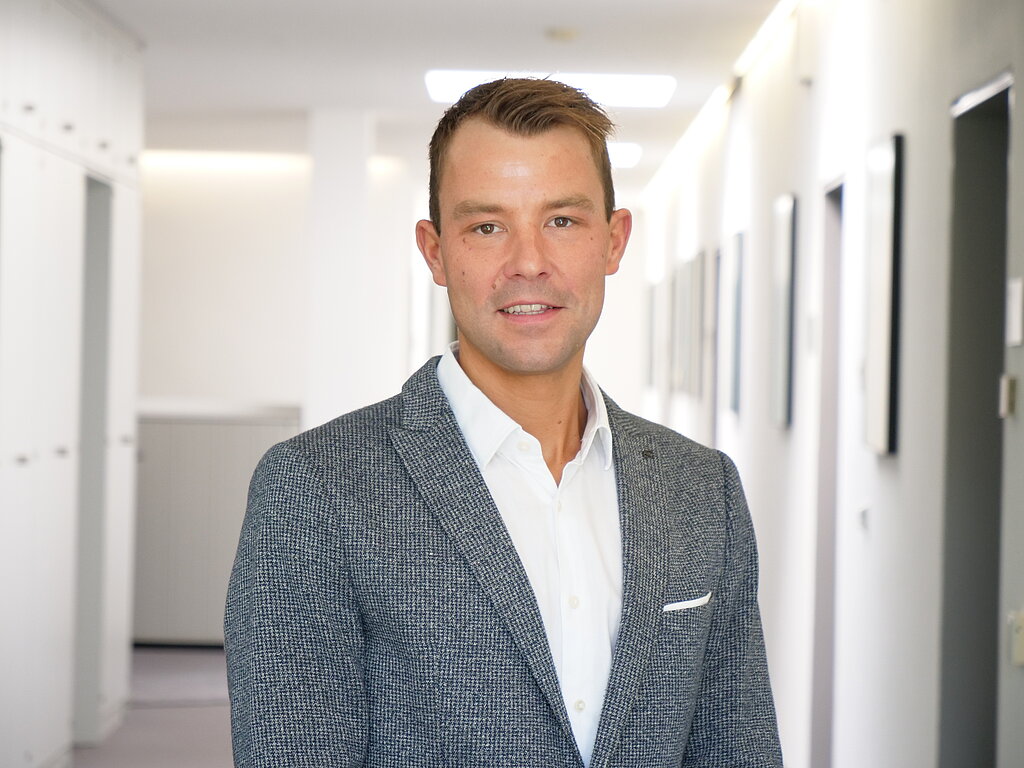 Portraitfoto: Klinikmanager Daniel Nauroth lächelt auf dem Foto und hat einen schönen Anzug an