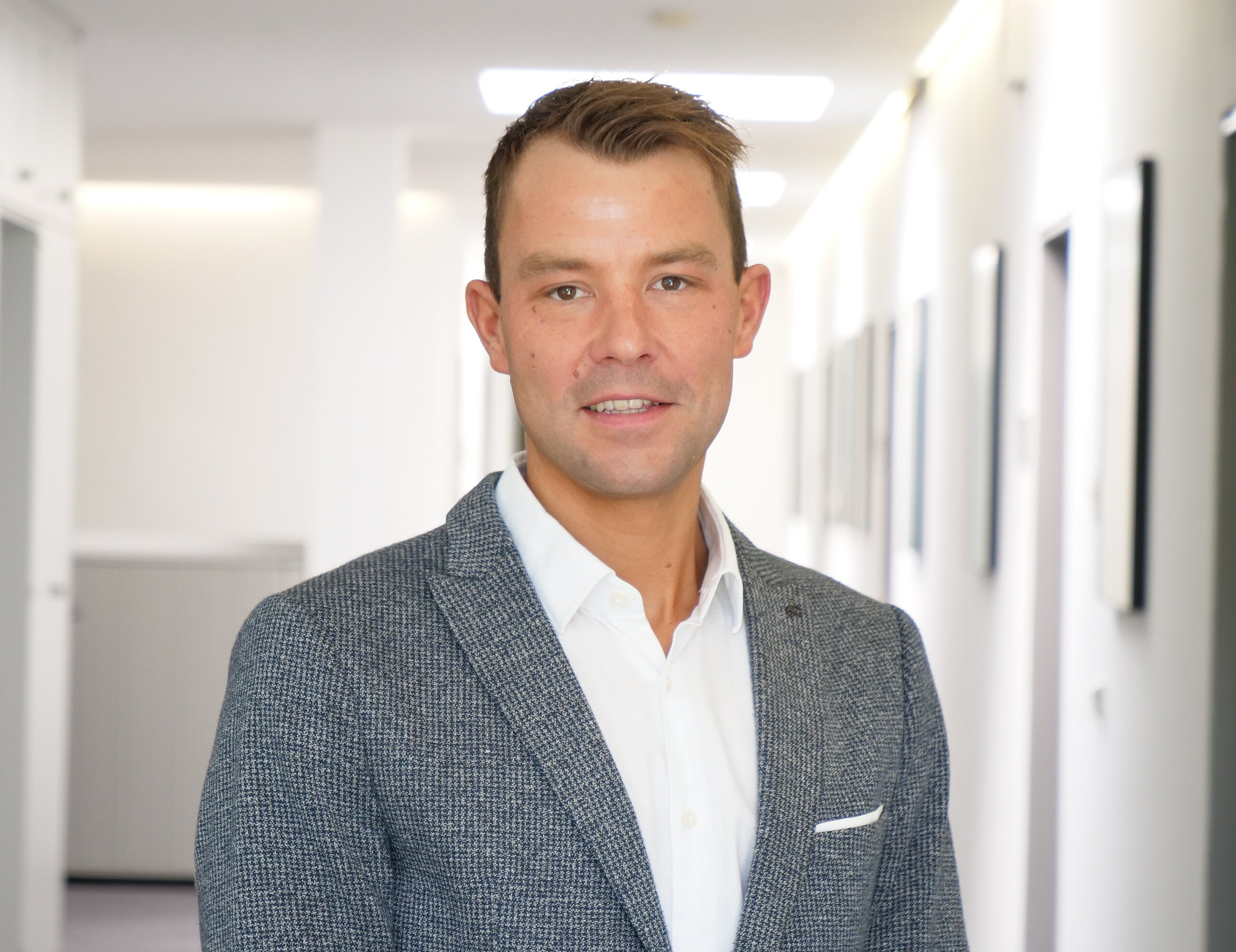 Portraitfoto: Klinikmanager Daniel Nauroth lächelt auf dem Foto und hat einen schönen Anzug an