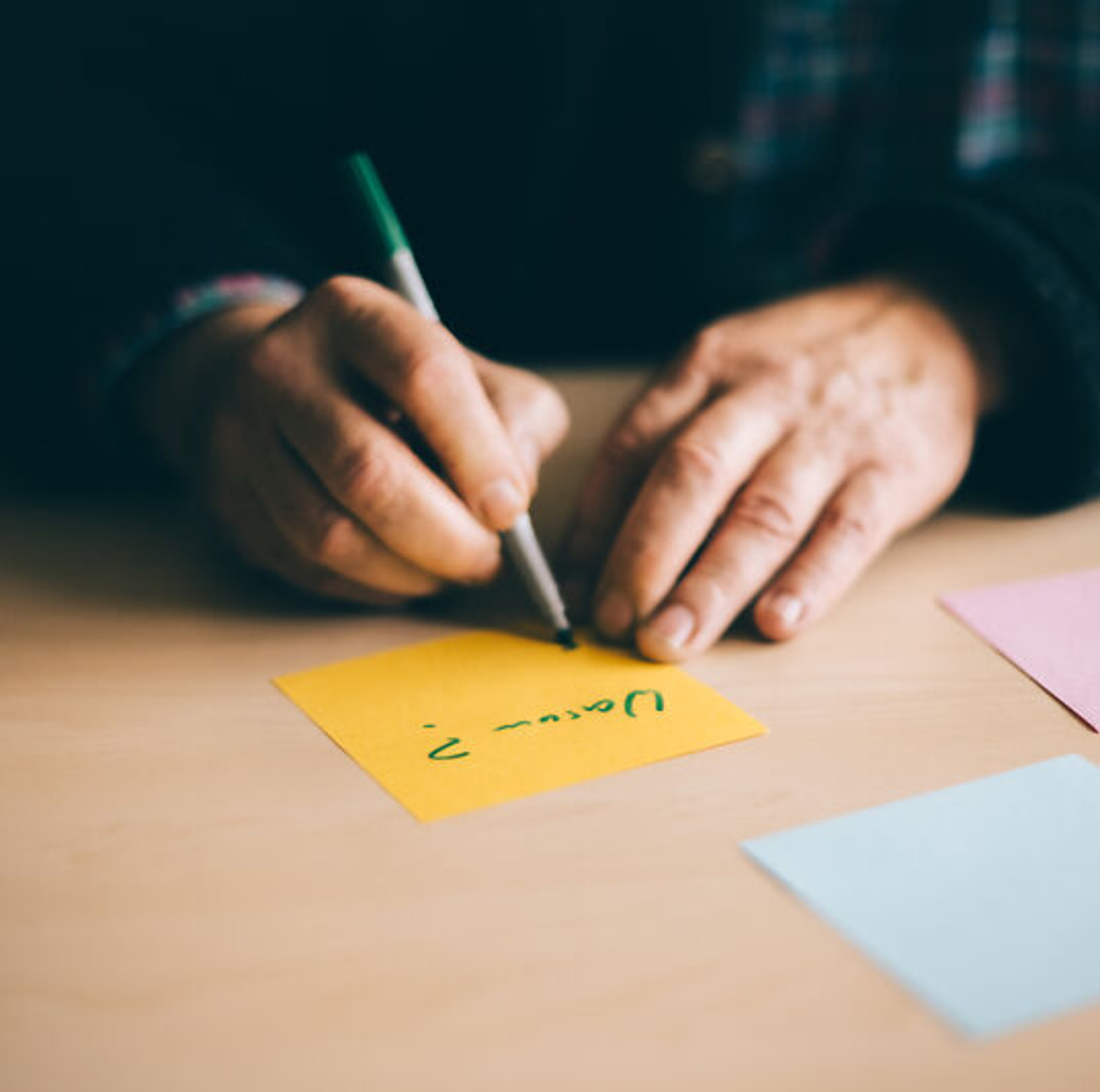 Jemand schreibt innerhalb einer Psychotherapie etwas auf mehrere bunte Zettel.