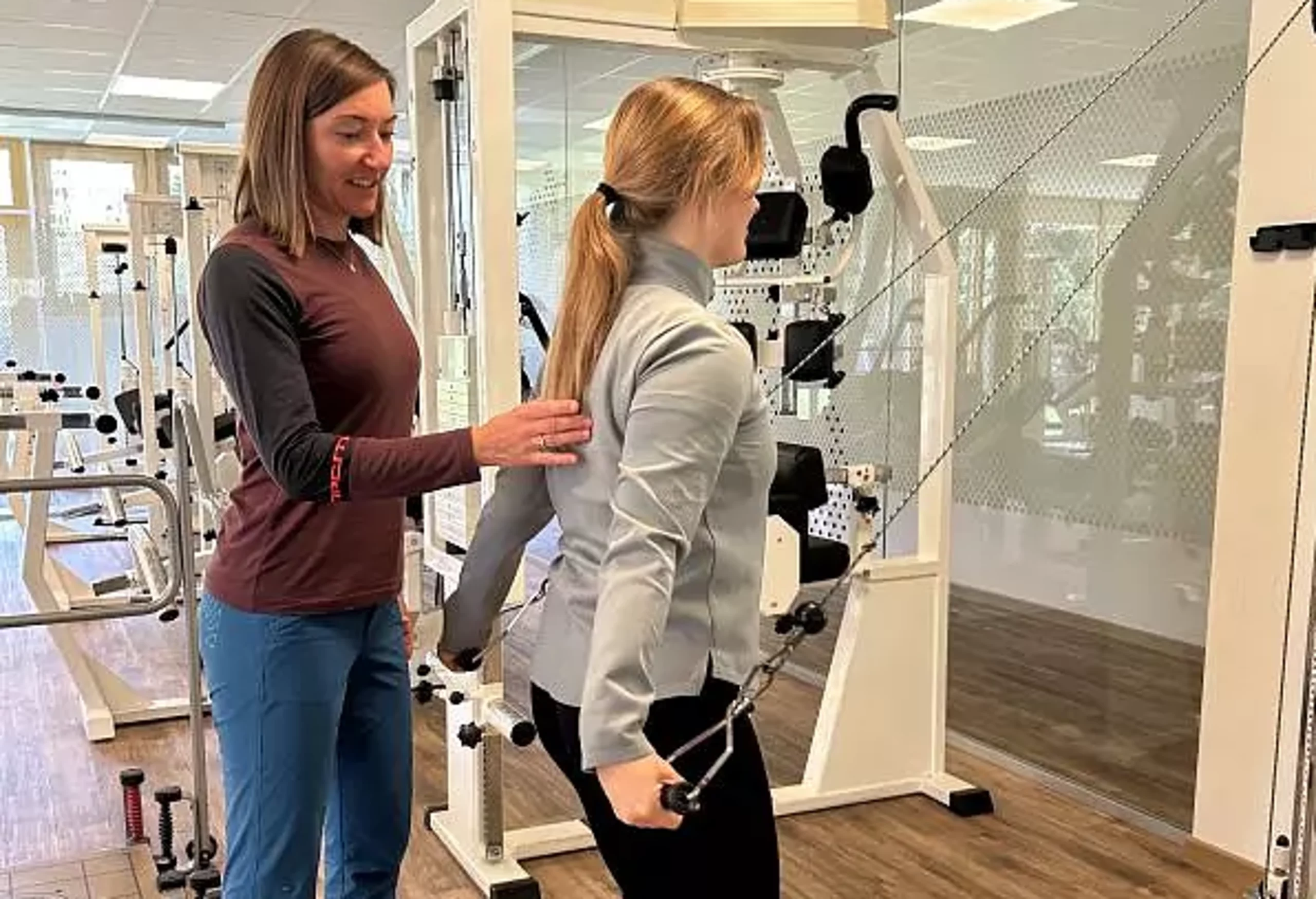 Betreuung MTT Training Eine Therapeutin betreut eine Patientin im MTT am Seilzug.
