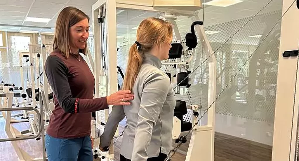 Betreuung MTT Training Eine Therapeutin betreut eine Patientin im MTT am Seilzug.