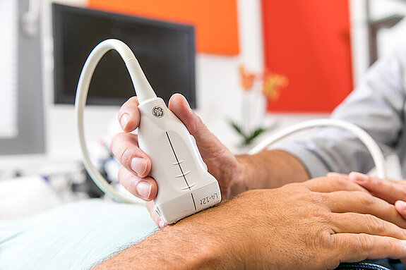 Eine Hand wir mit einem Ultraschallgerät behandelt.