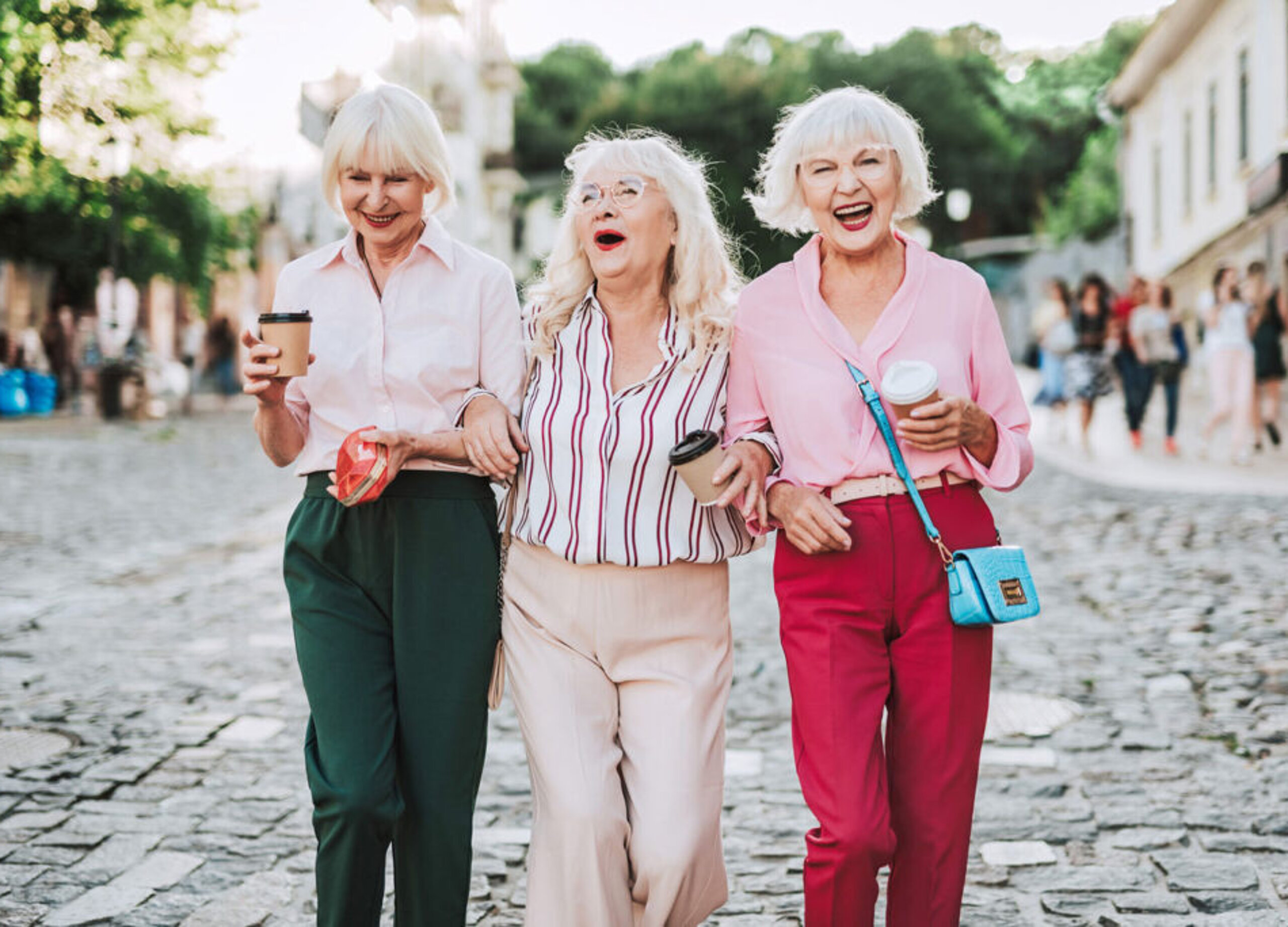 Drei ältere Damen in der Fußgängerzone lachend.