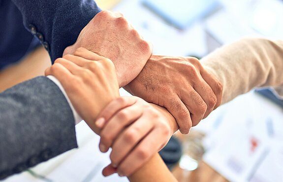 Hände Teamwork Vier Hände greifen ineinander.
