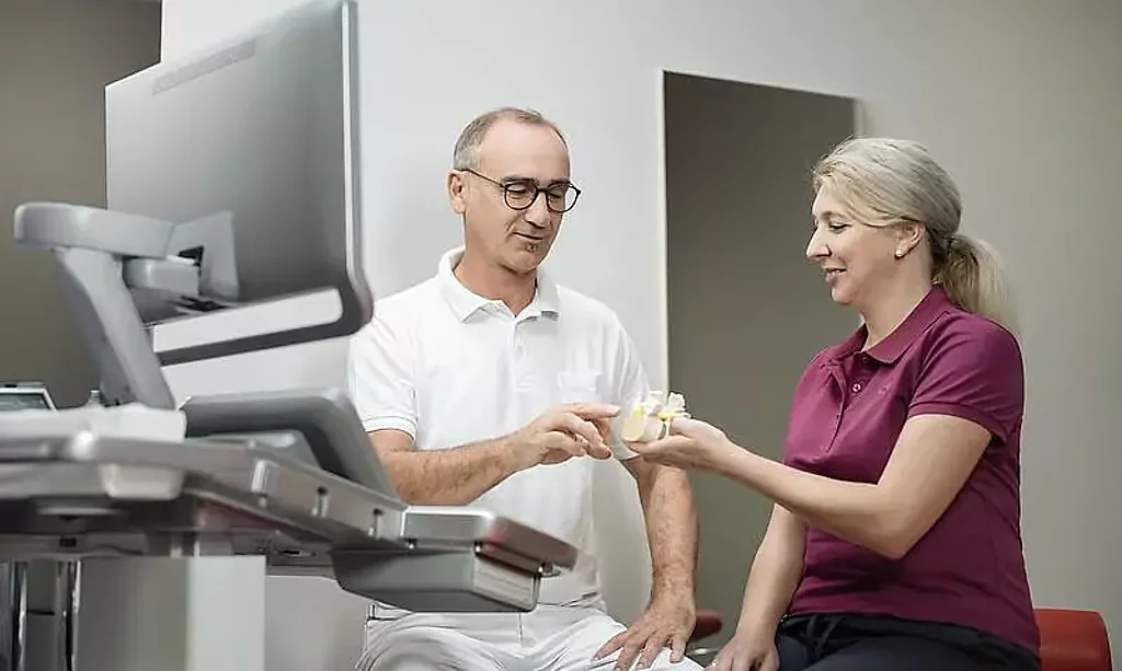 Ein Arzt zeigt einer Patientin etwas an einem Knochenmodel.