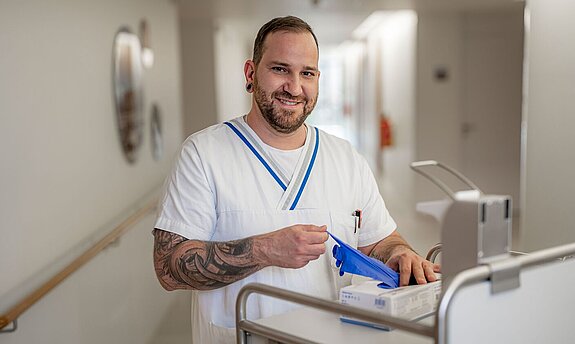 Ein freundlich lächelnder Pfleger zieht sich Einmalhandschuhe an.