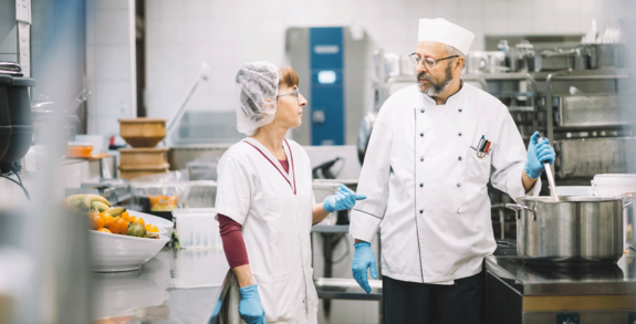 Küchenhilfen Frau Gantner-Gehbauer unterhält sich mit dem Küchenchef.
