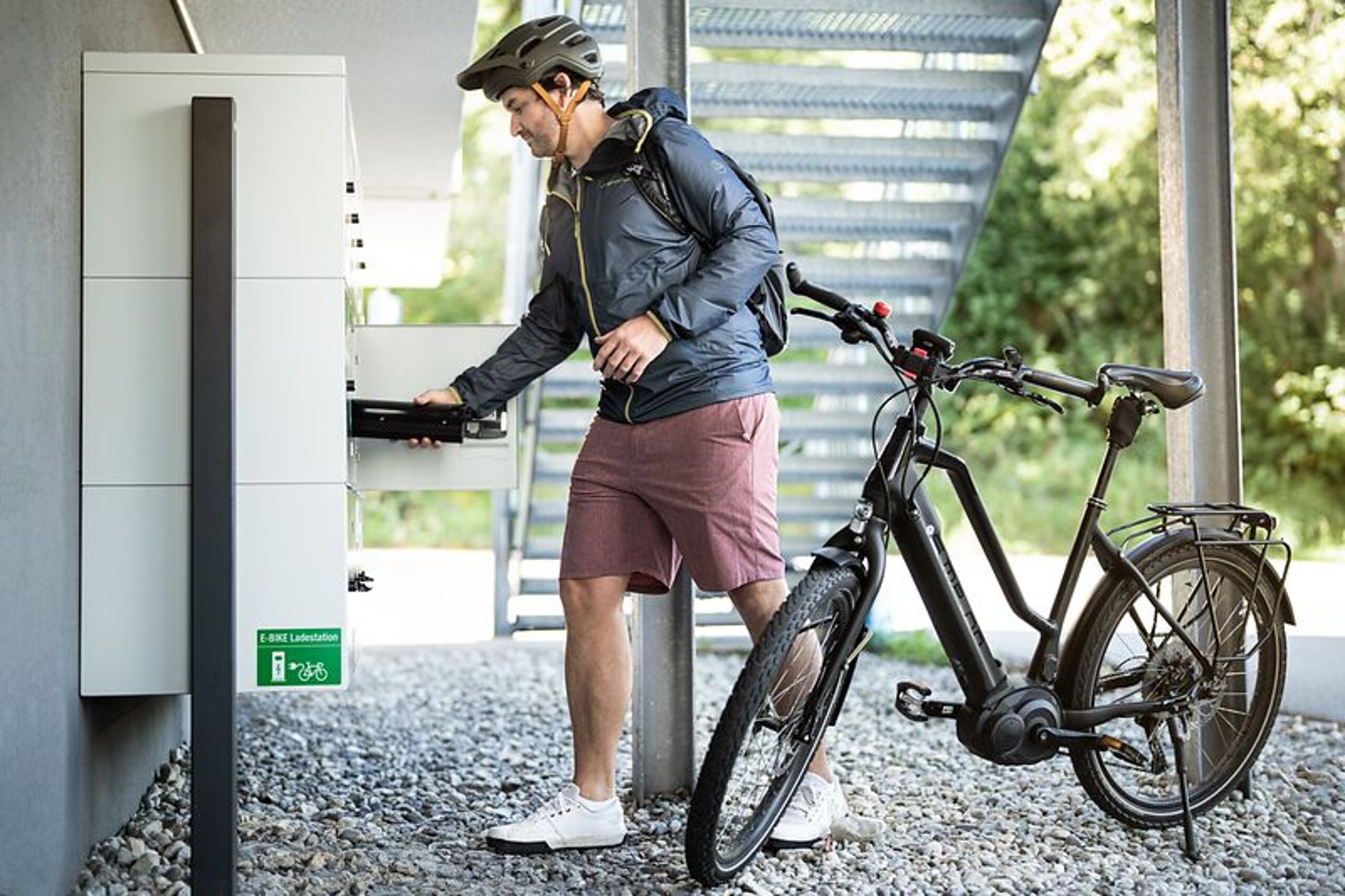 Nachhaltigkeit Ein Mann schließt sein E-Bike an der Ladestation an.