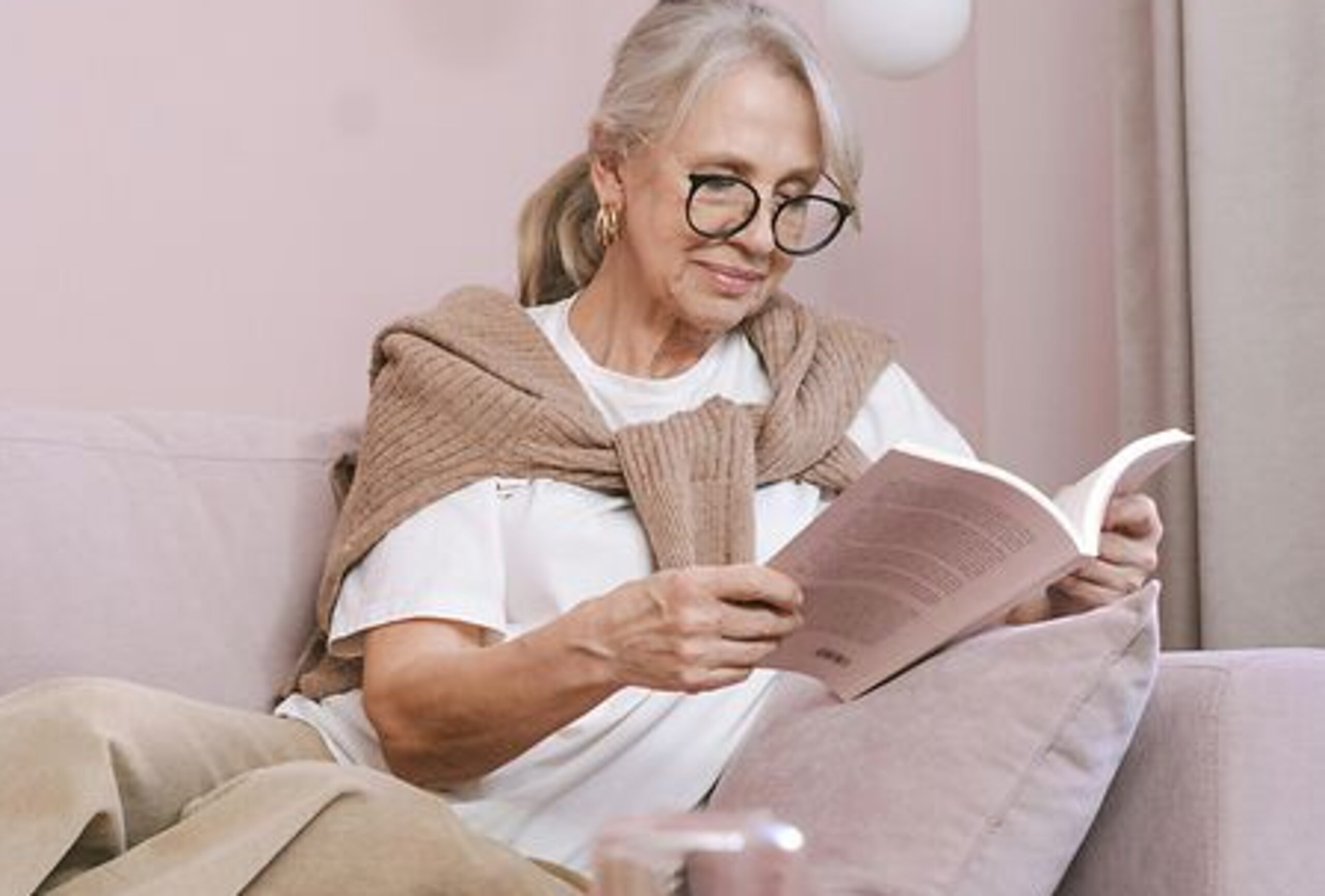 Eine Frau ließt zuhause ein Buch auf dem Sofa.
