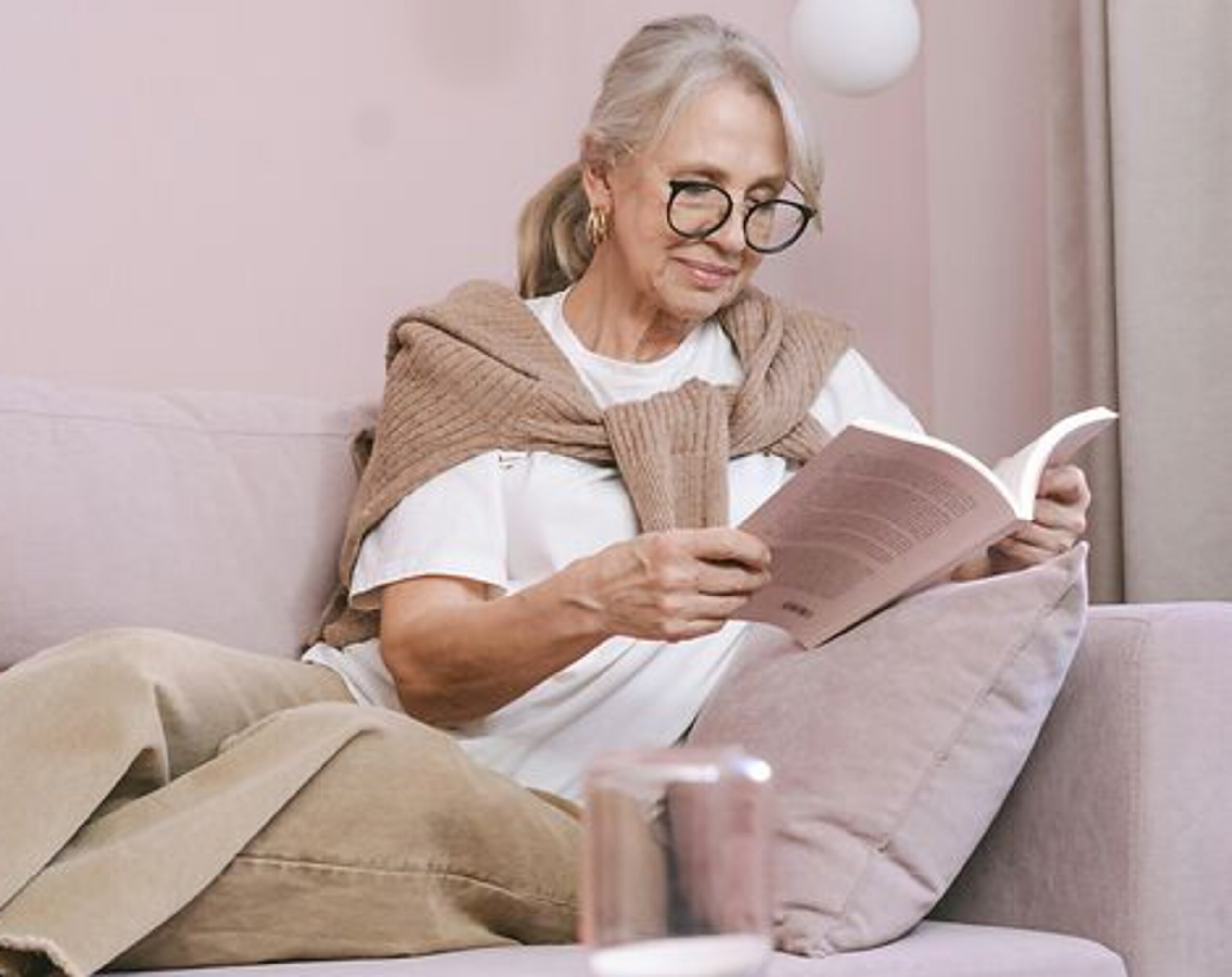 Eine Frau ließt zuhause ein Buch auf dem Sofa.