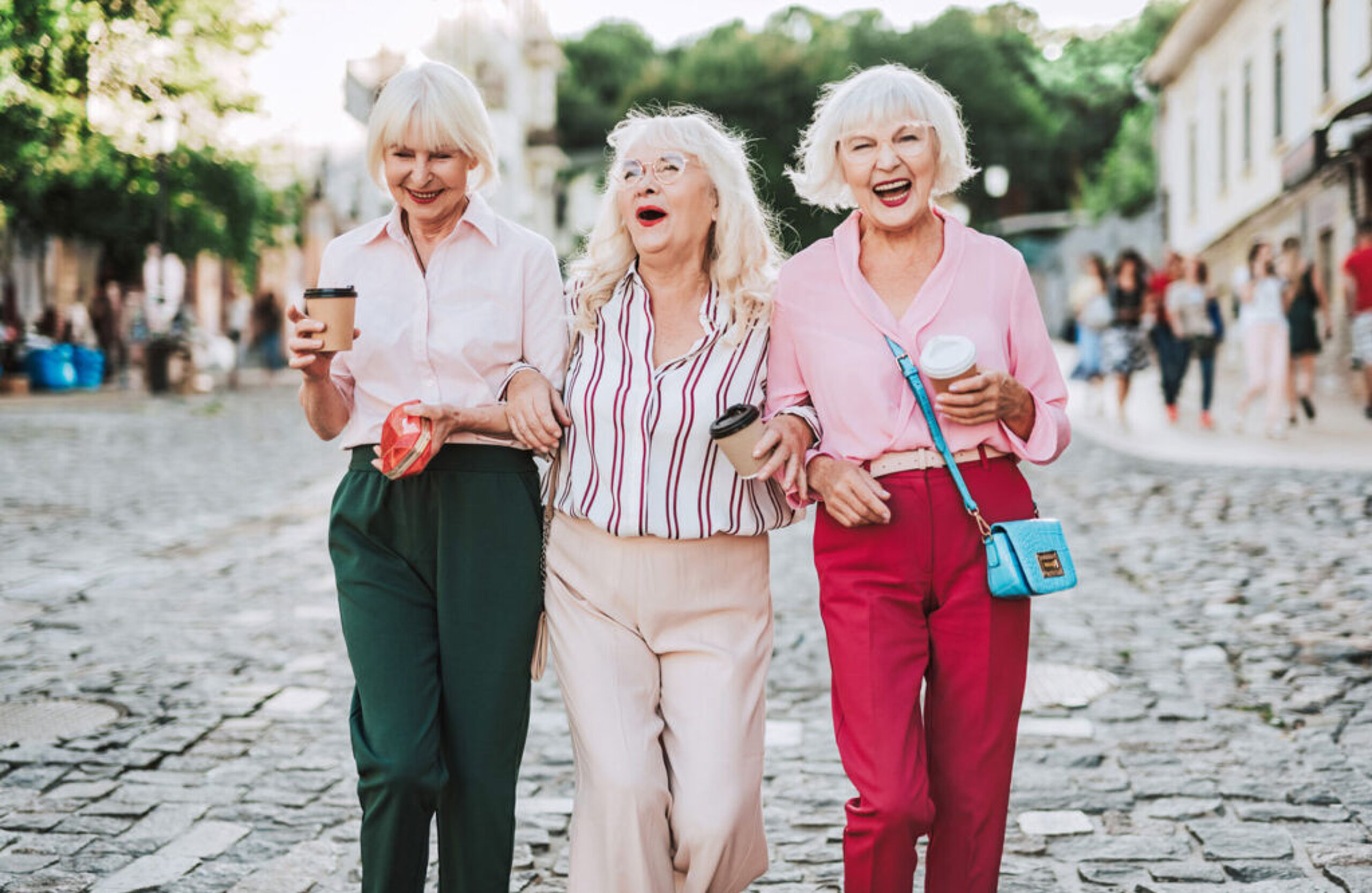 Seniorinnen Drei Seniorinnen laufen lachend durch die Straße.