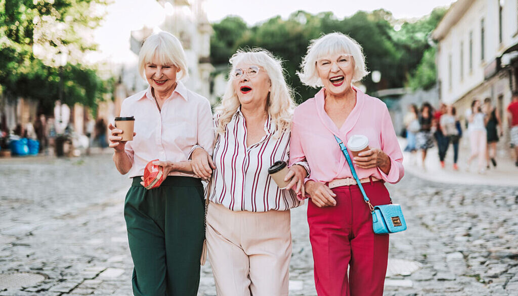 Seniorinnen Drei Seniorinnen laufen lachend durch die Straße.