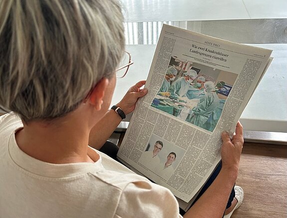 Frau liest in der Schwäbischen Zeitung vom 25. August 2026 den Artikel „Wie zwei Krankenhäuser Landesgrenzen einreißen“.