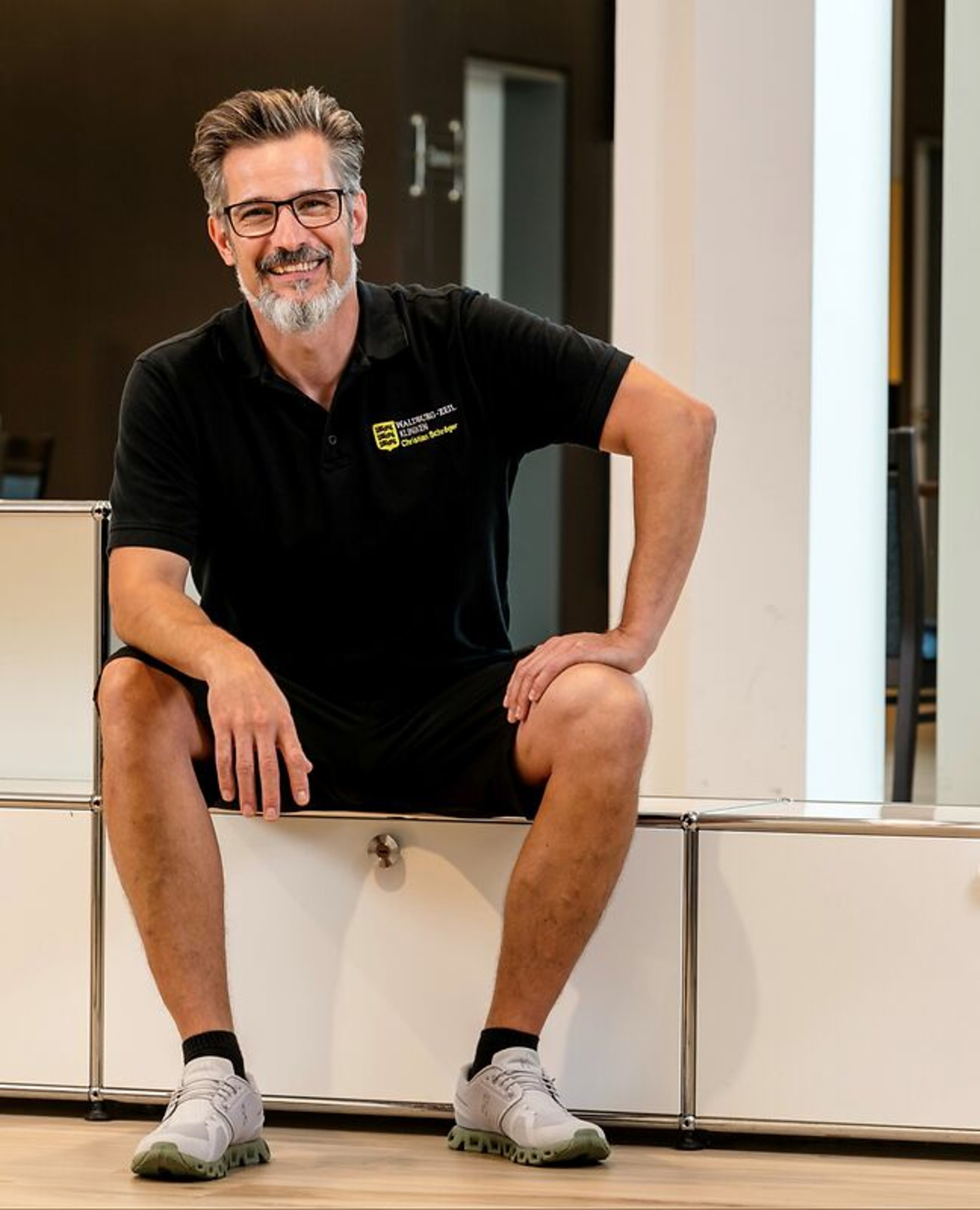 Christian Schröger sitzt und lacht in die Kamera.