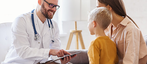 Ein freundlicher Arzt berät eine Mutter mit Sohn.