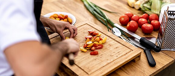 Männerhände die gerade auf dem Schneidebrett das Essen zubereitet
