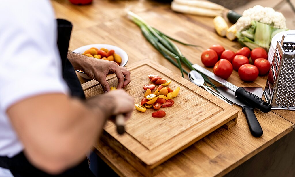 Männerhände die gerade auf dem Schneidebrett das Essen zubereitet