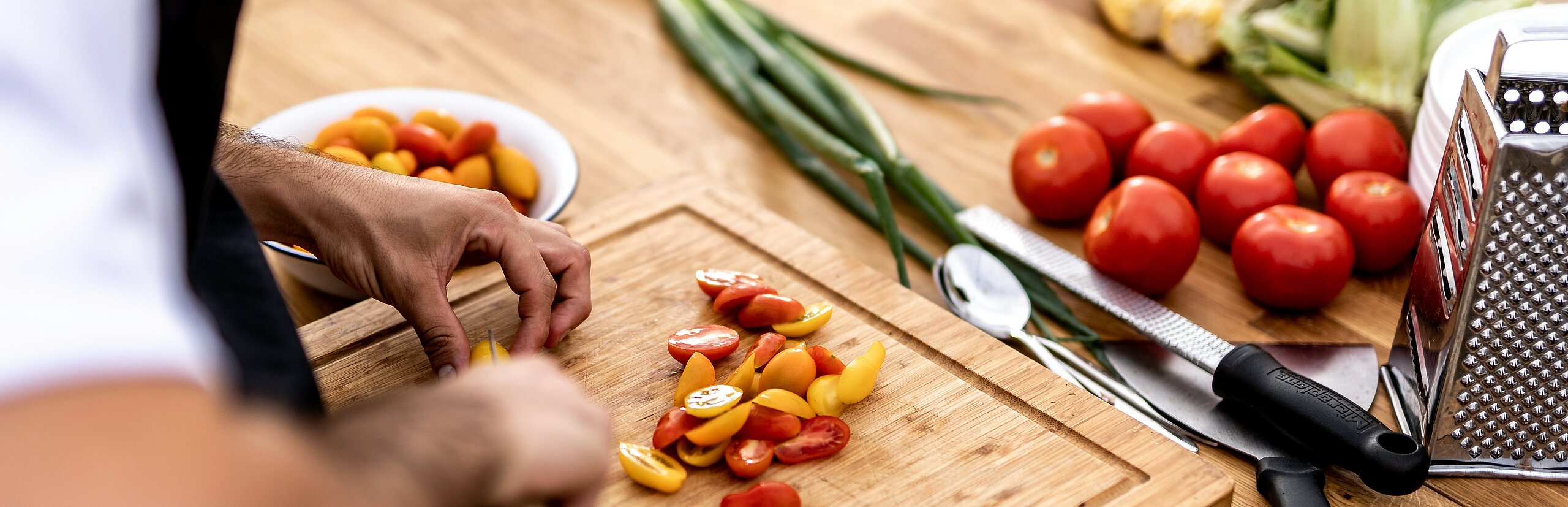 Männerhände die gerade auf dem Schneidebrett das Essen zubereitet