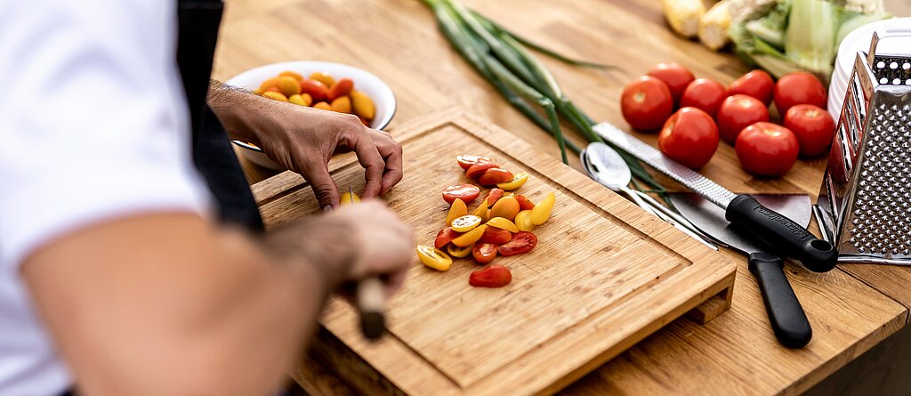 Männerhände die gerade auf dem Schneidebrett das Essen zubereitet