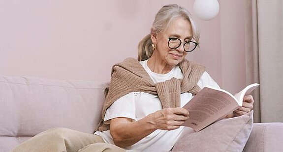 Frau ließt ein Buch Eine Frau ließt zuhause ein Buch auf dem Sofa.