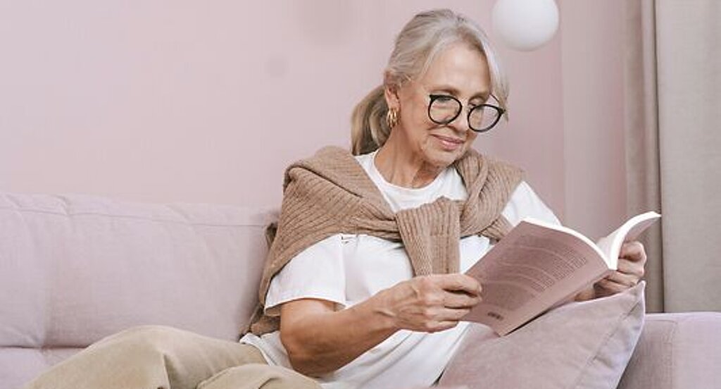Frau ließt ein Buch Eine Frau ließt zuhause ein Buch auf dem Sofa.