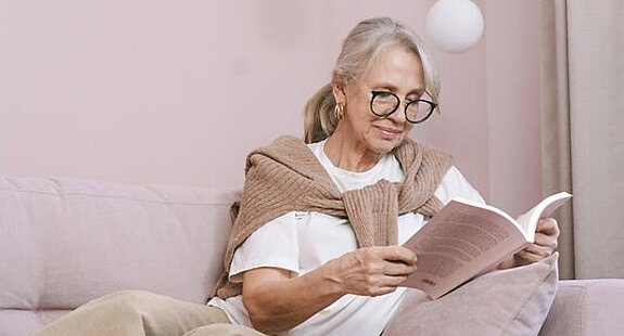 Frau ließt ein Buch Eine Frau ließt zuhause ein Buch auf dem Sofa.