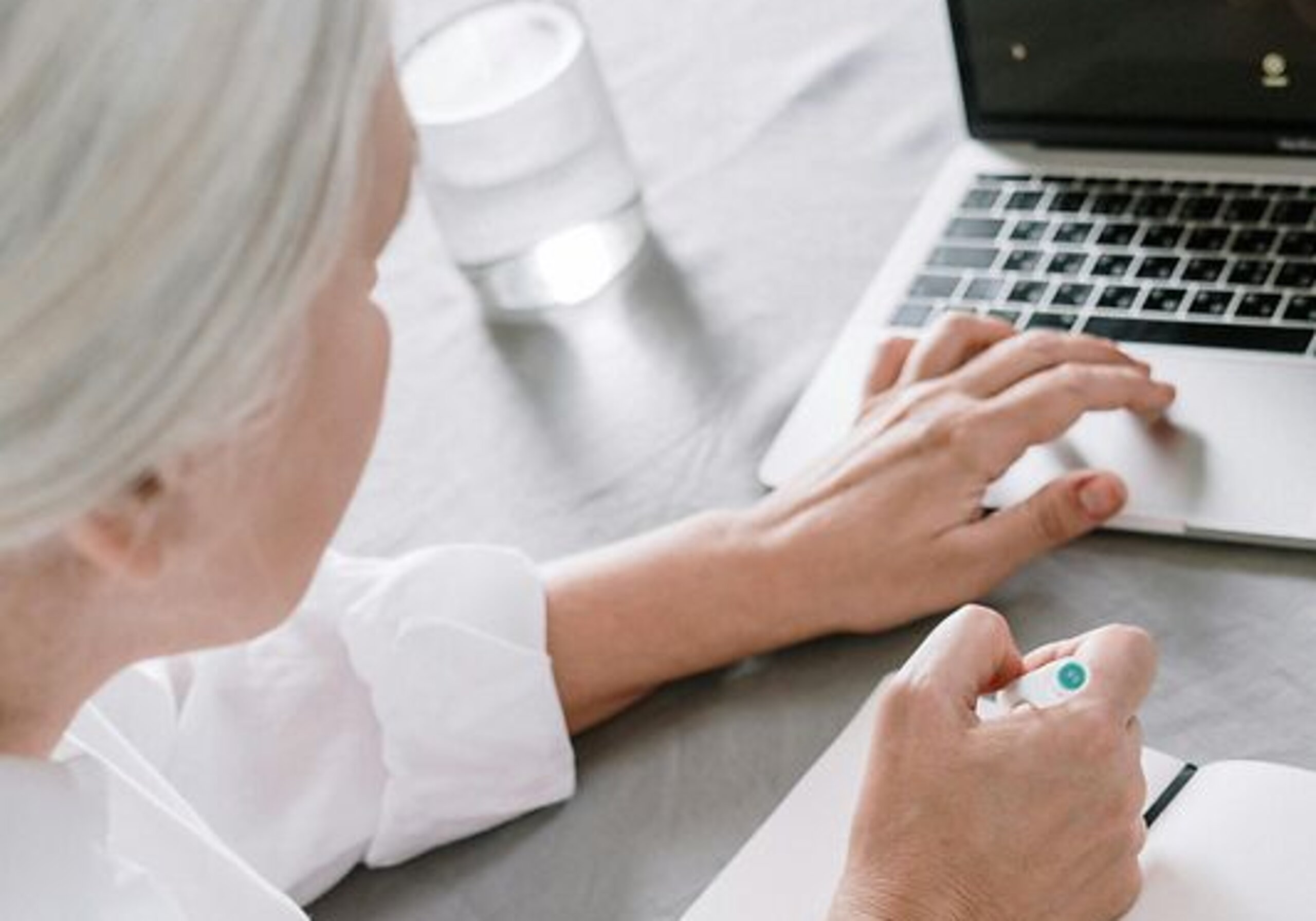 Eine Person recherchiert am Laptop und macht sich Notizen.