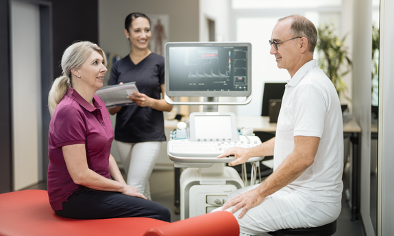 Ein älterer Patient im Gespräch mit medizinischem Personal in einer Arztpraxis.