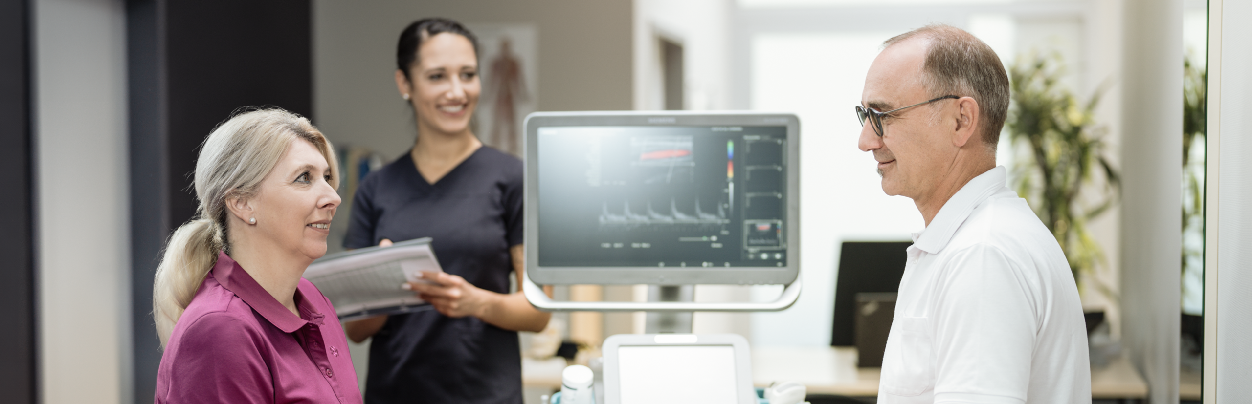 Ein älterer Patient im Gespräch mit medizinischem Personal in einer Arztpraxis.