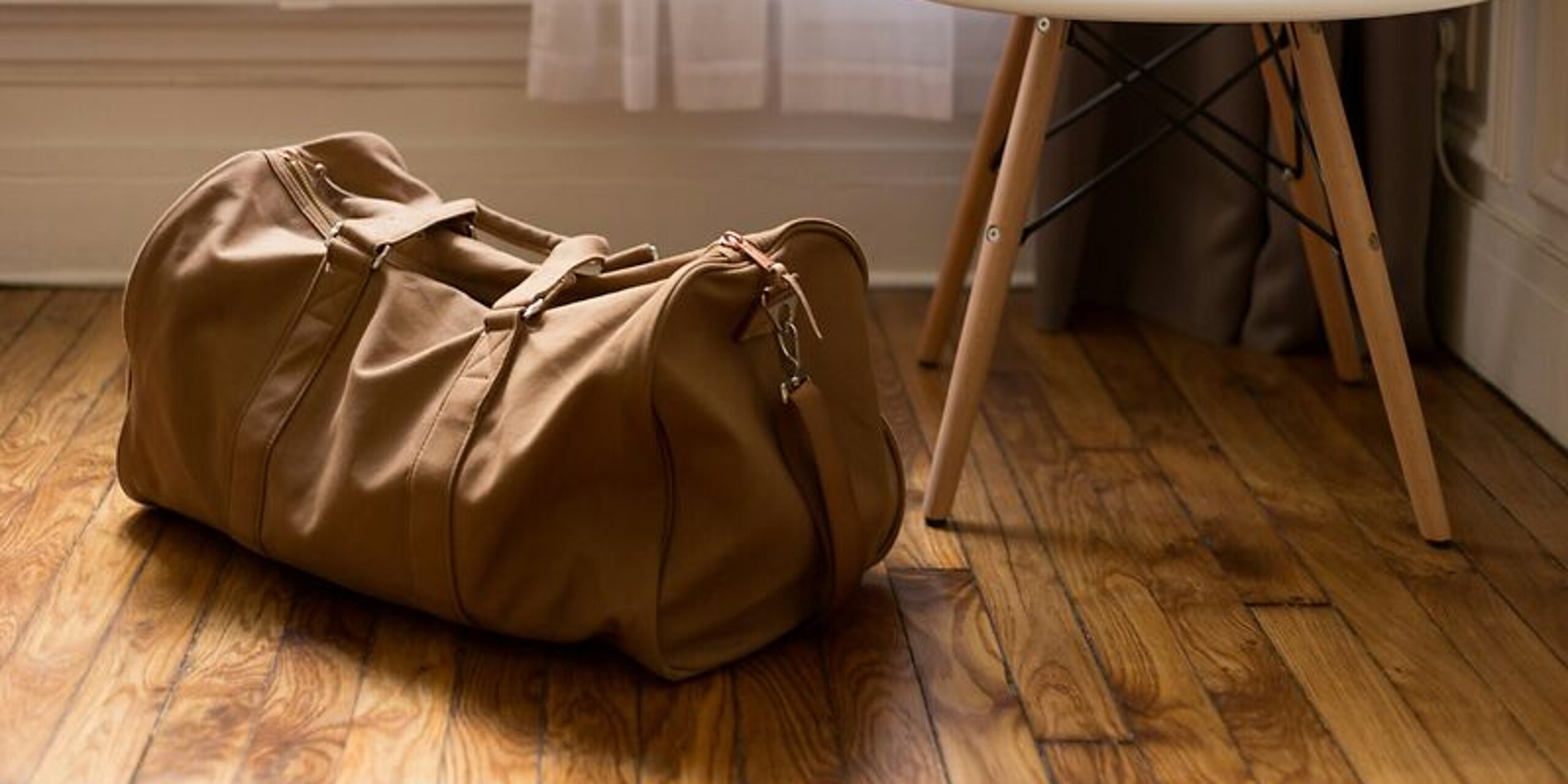 Eine braune Sporttasche steht auf dem Boden in einem Zimmer.