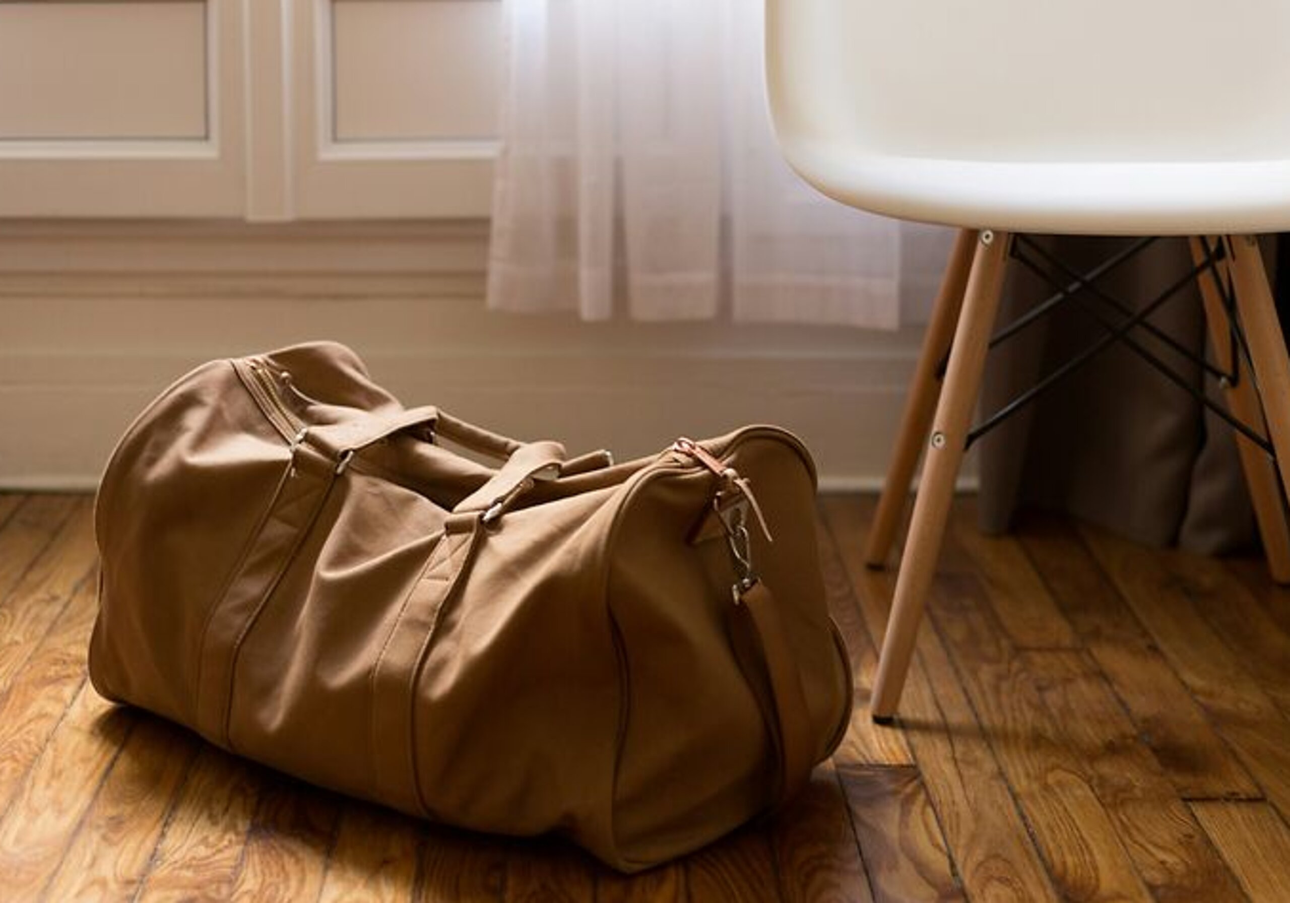 Eine braune Sporttasche steht auf dem Boden in einem Zimmer.