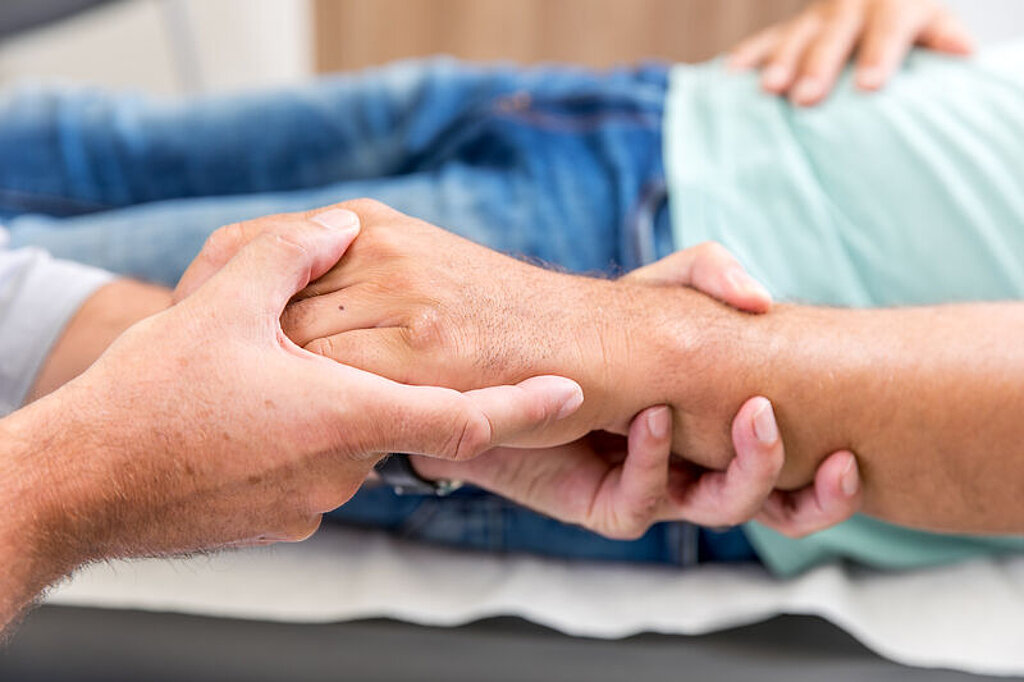 Ein Arzt umfasst die Hand eines Patienten.