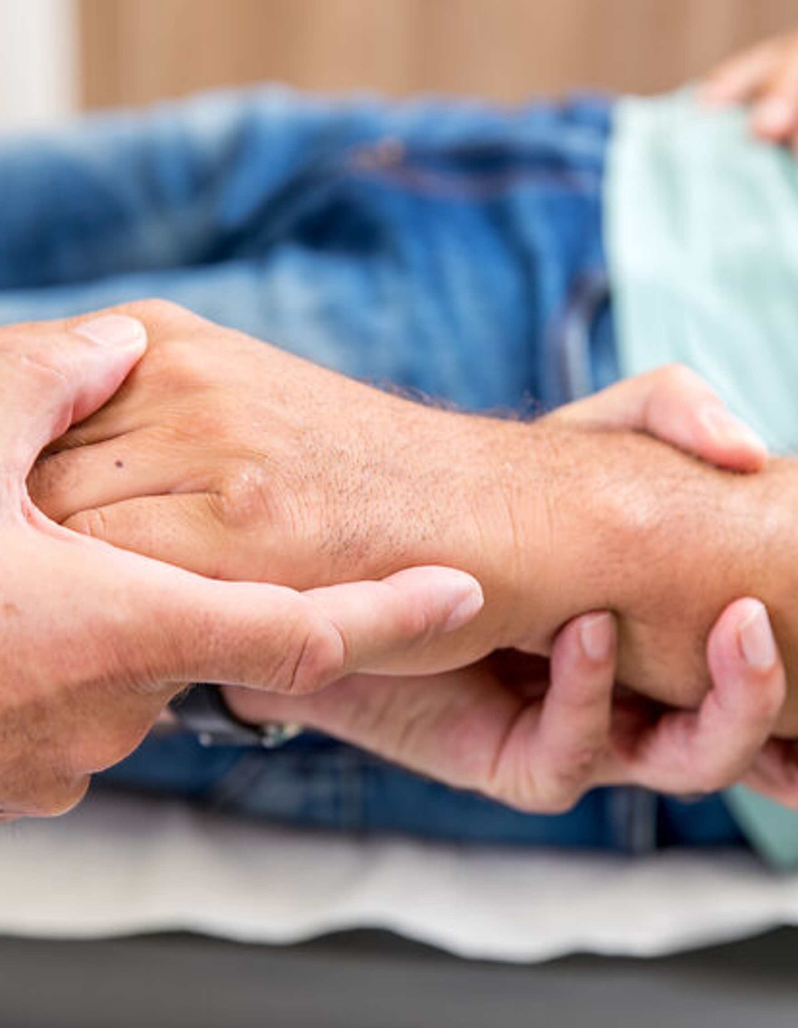 Ein Arzt umfasst die Hand eines Patienten.