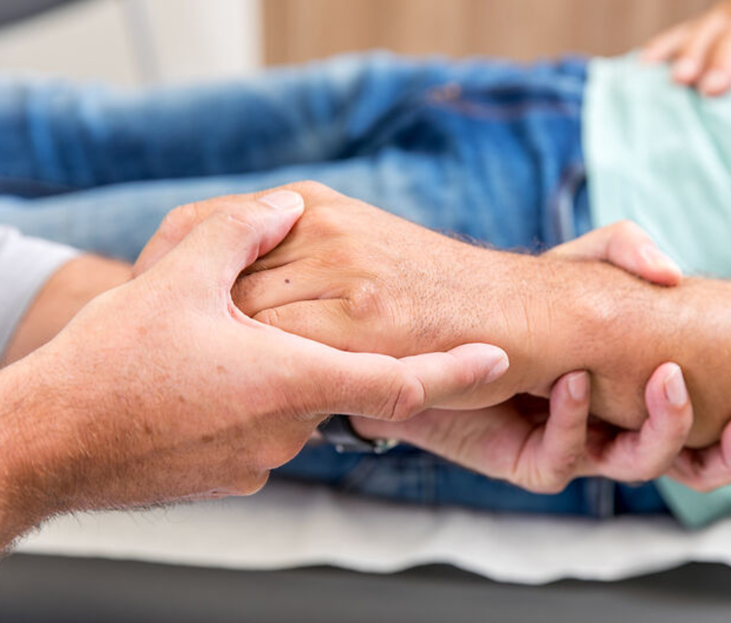 Ein Arzt umfasst die Hand eines Patienten.