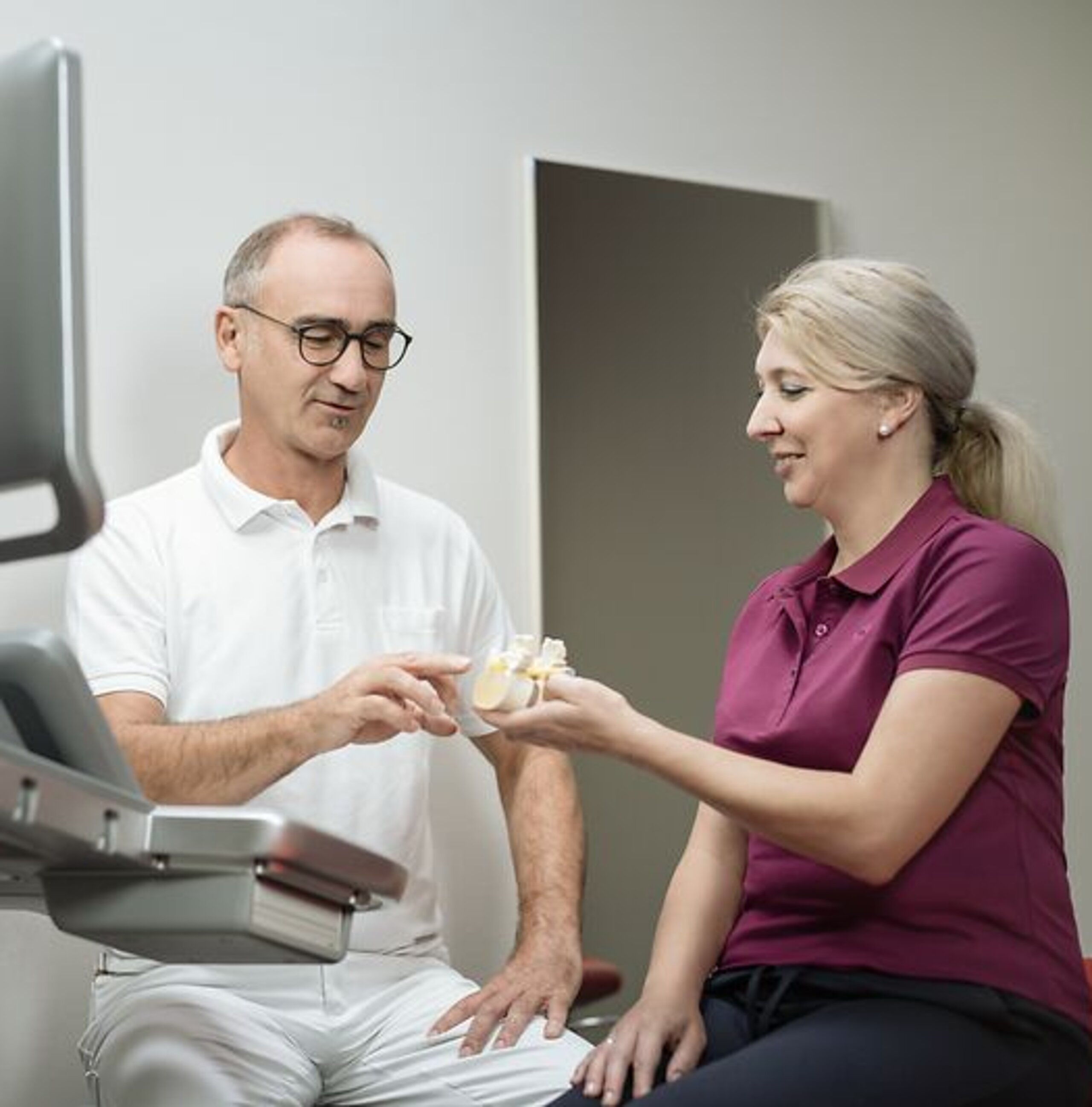 Ein Arzt erklärt einer Patientin etwas an einem Knochenmodel.