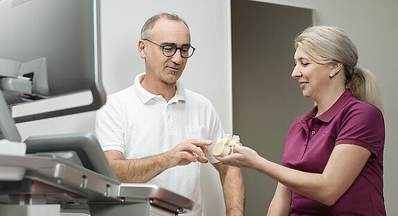 Ein Arzt erklärt einer Patientin etwas an einem Knochenmodel.